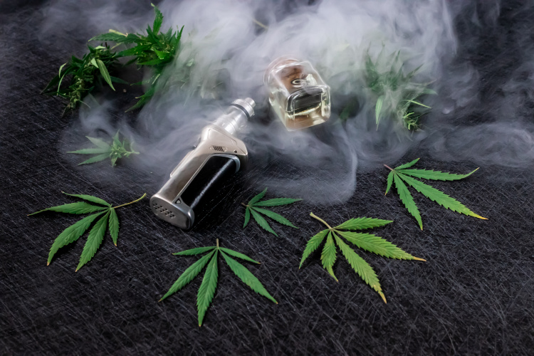 Cannabis vape device with cartridge surrounded by cannabis leaves and vapor