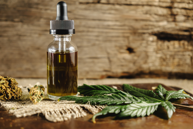 Cannabis tincture bottle with cannabis flower and leaves