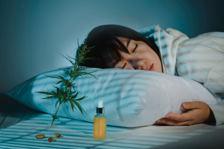 Person sleeping beside cannabis tincture, capsules and cannabis plant