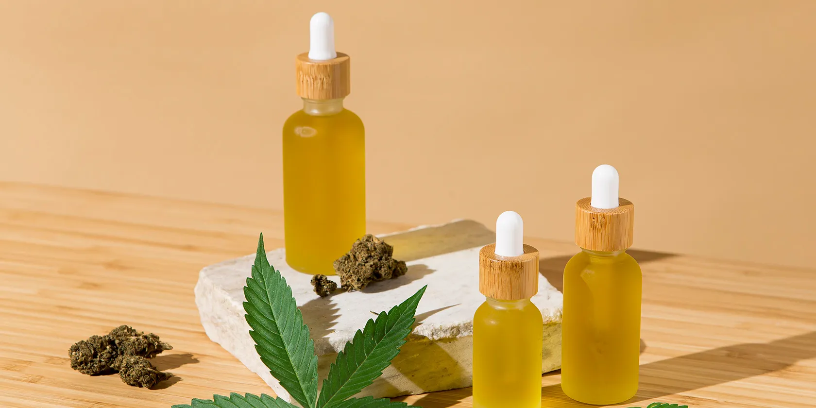 MCT oil bottles with cannabis flower on wooden surface